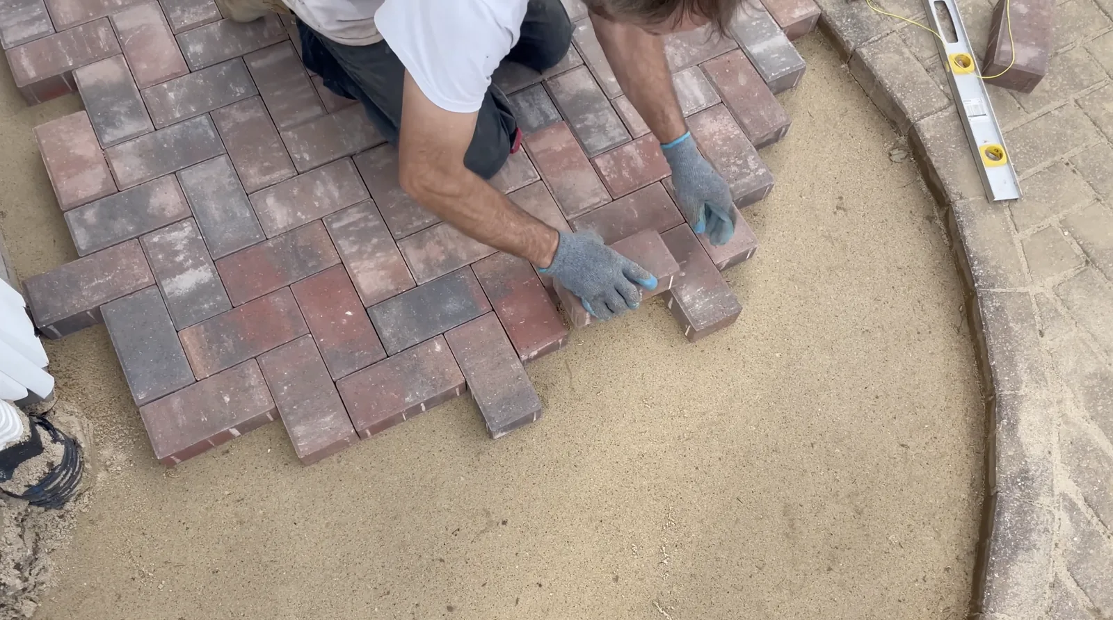 Installer laying herringbone pattern pavers by hand